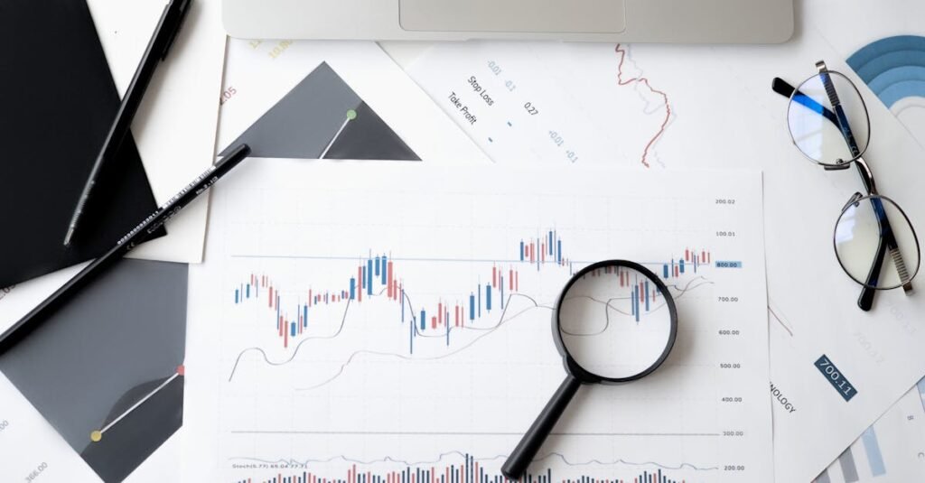 Flat lay of stock market analysis documents with magnifying glass, pens, and glasses.