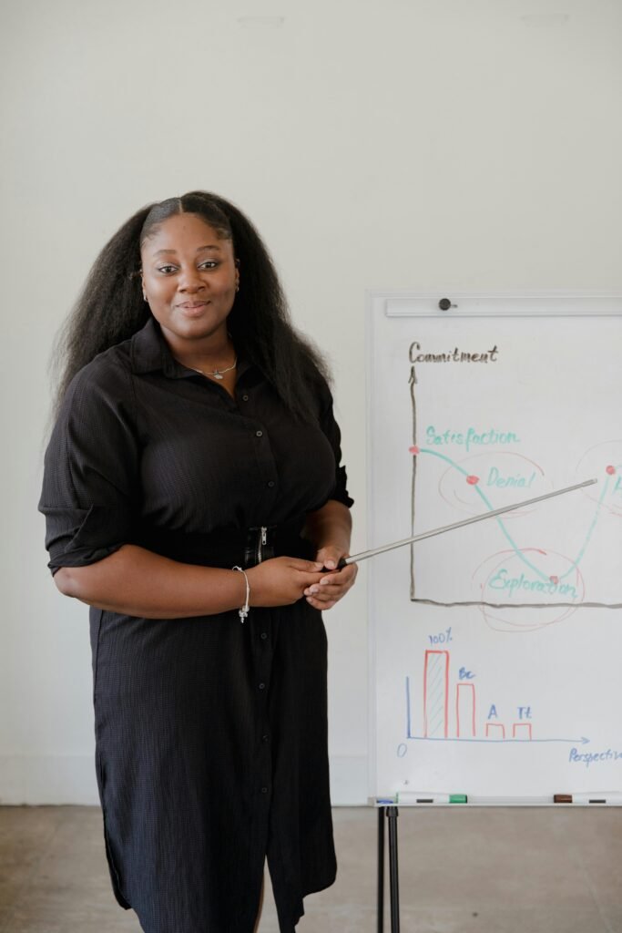 African American woman presenting business data on a flipchart in an office setting.